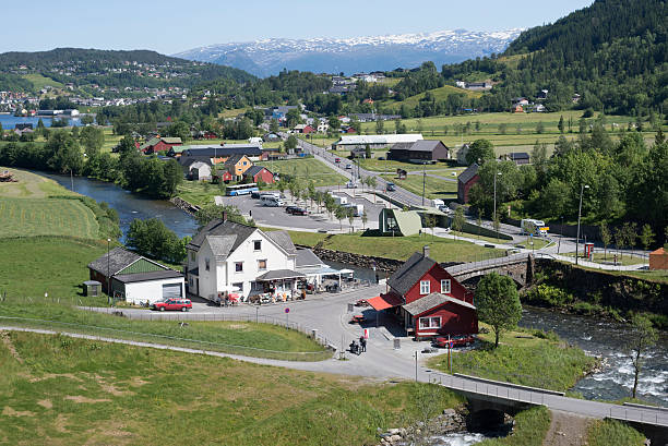 Kvam, Norway - June 8, 2016: View of Kvam with its town in a valley surrounded by mountains during sunny day. The vantage point is next to a popular tourist attraction, Steinsdalsfossen, a large waterfall with a footpath underneath. 