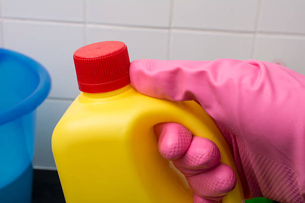 household chemical bottle in pink washing up glove household yellow chemical bleach bottle with red cap in pink washing up glove and blue bucket bleach stock pictures, royalty-free photos & images