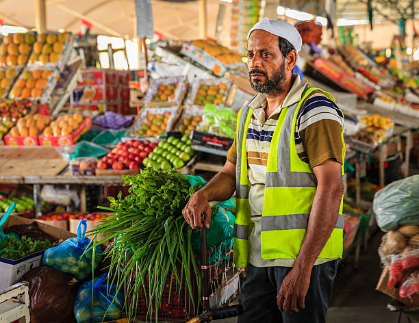 Dubai, UAE - June 4, 2016: a delivery worker with a cart full of fresh produce at the fruit and vegetable market in Dubai, UAE