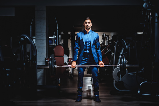 Man in suit lifting heavy weight in the gym