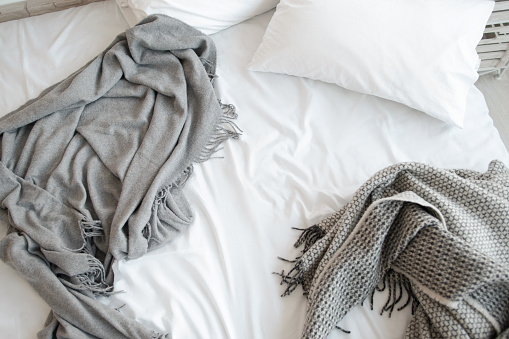 Cama sin hacer con almohada y mantas grises vista superior photo