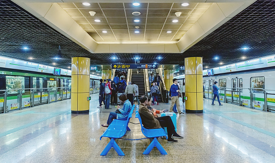 Shanghai, China - April 29, 2015: Group of people sitting on bench waiting for their train in subway station of Shanghai, China. 