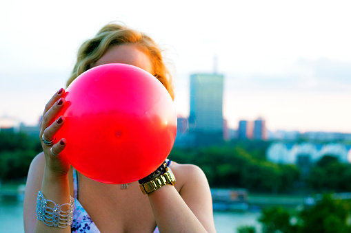 woman inflating balloon. Girl holding balloon near face.