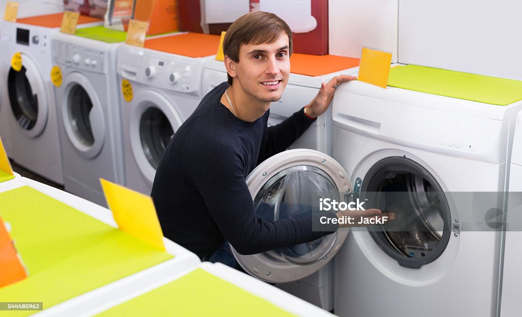 Man choosing new laundry machine Smiling male customer looking at washers and dryers in store Appliance Stock Photo