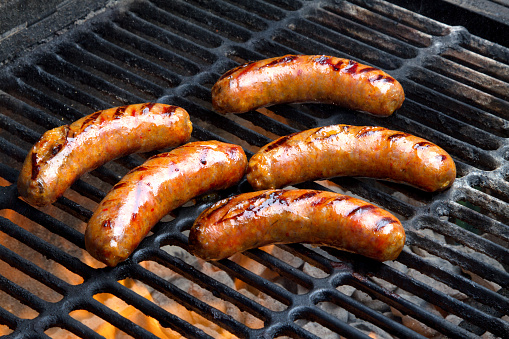 Juicy Bratwurst, brown and hot over a charcoal fire with grill marks