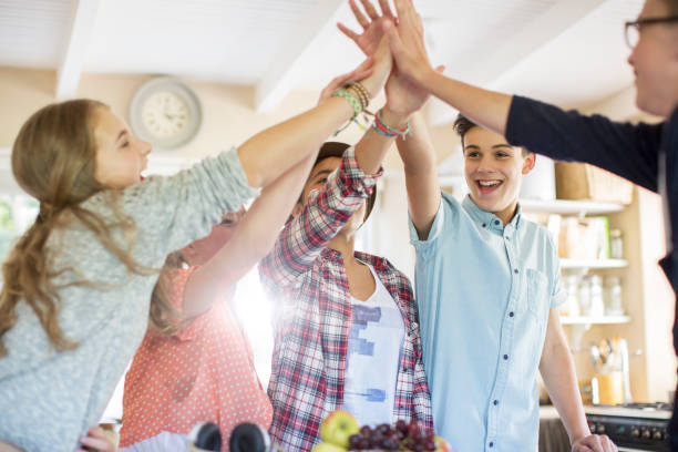 Group of teenagers doing high five in living room stock photo