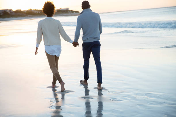 istock Young couple holding hands and walking on beach 544489257