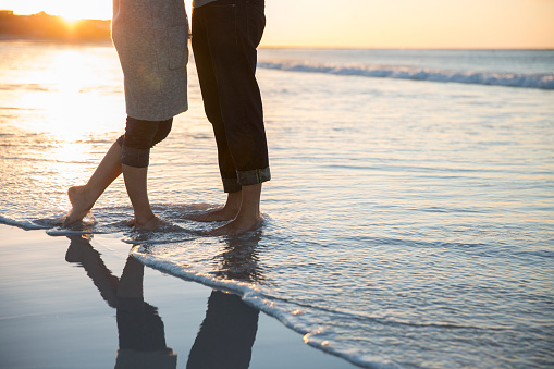 Piernas de una joven pareja de pie en la playa photo