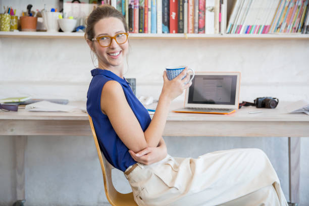 istock Young woman sitting with mug in home office 544489551