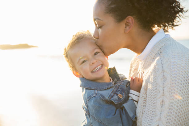 istock Mother kissing daughter on beach 544489635