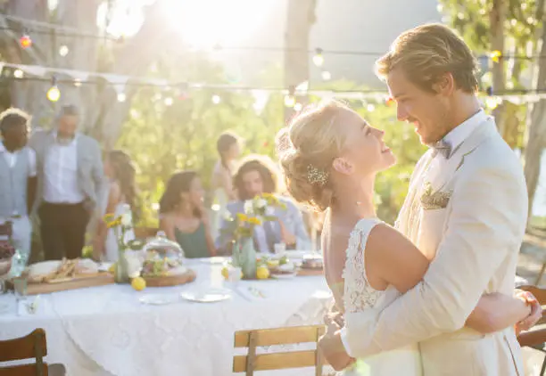 Photo of Young couple dancing during wedding reception in domestic garden