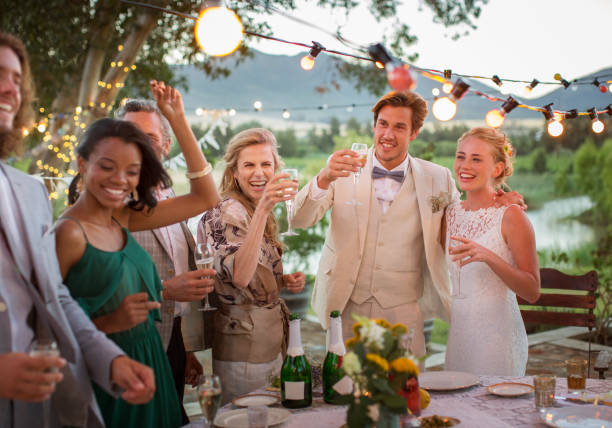 pareja joven e invitados brindando con champán durante la recepción de la boda en el jardín doméstico - invitado de boda fotografías e imágenes de stock