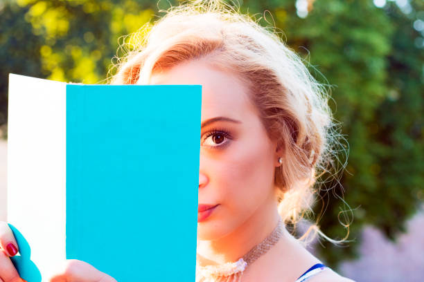 istock Young woman hiding behind a book 544557726