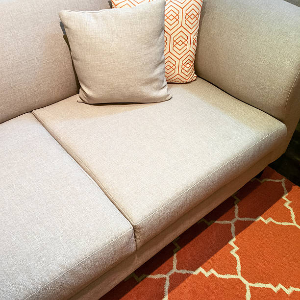 istock Gray sofa with cushions on orange carpet 544559782