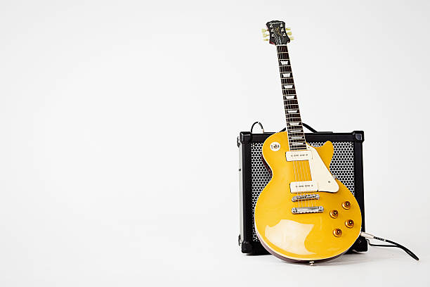 '56 Les Paul Pro electric guitar leaning on Roland amp Cape Town, South Africa - June 29, 2016: A '56 Les Paul Pro electric guitar in goldtop finish, manufactured in 2014 by Epiphone, a brand of the US-based Gibson corporation. This instrument is an authentic, authorized reproduction of a 1956-vintage Gibson model, complete with a fat neck profile and P-90 pickups of the type originally fitted to the Les Paul before their replacement by humbuckers in the late 1950s. P-90 pickups are riding the modern retro wave and returning to favor among guitarists. The guitar is leaning against a Roland Cube 80X amplifier. Ample copy space to the left of the guitar. amplifier plug stock pictures, royalty-free photos & images