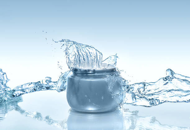 the blue jar of moisturizing cream with big water splas - moisten imagens e fotografias de stock