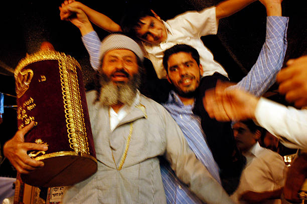 Sderot, Israel - October 14, 2006: Orthodox Jewish Men celebrate Simchat Torah by dancing with the scrolls of the Torah at a Synagogue in Sderot, Israel. Simchat Torah is a celebratory Jewish holiday that marks the completion of the annual Torah reading cycle.