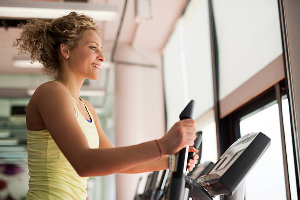 Smiling athletic woman practicing on exercise machine in gym.