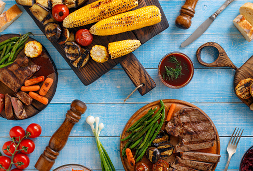 Variation food cooked on the grill on a wooden table, fillet steak grilled served with grilled vegetables. Outdoors Food Concept