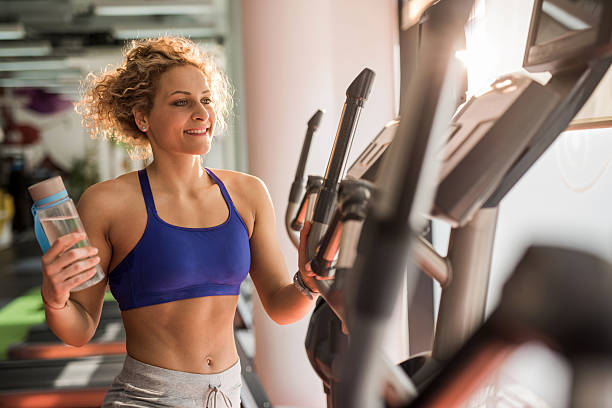istock Smiling athletic woman standing with water bottle in a gym. 544576558