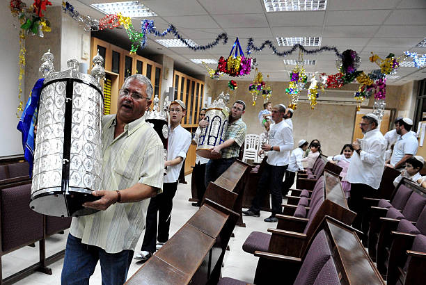 Celebrating Jewish Holiday Simchat Torah in a Synagogue Sderot, Israel - October 11, 2015: Israeli Jewish men celebrate Simchat Torah by dancing with the scrolls of the Torah at a Synagogue in Sderot, Israel. Simchat Torah is a celebratory Jewish holiday that marks the completion of the annual Torah reading cycle. simchat torah photos stock pictures, royalty-free photos & images