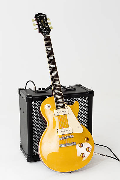 '56 Les Paul Pro electric guitar with Roland Cube amp Cape Town, South Africa - June 29, 2016: A '56 Les Paul Pro electric guitar in goldtop finish, manufactured in 2014 by Epiphone, a brand of the US-based Gibson corporation. This instrument is an authentic, authorized reproduction of a 1956-vintage Gibson model, complete with a fat neck profile and P-90 pickups of the type originally fitted to the Les Paul before their replacement by humbuckers in the late 1950s. P-90 pickups are riding the modern retro wave and returning to favor among guitarists. The guitar is leaning against a Roland Cube 80GX amplifier. amplifier plug stock pictures, royalty-free photos & images