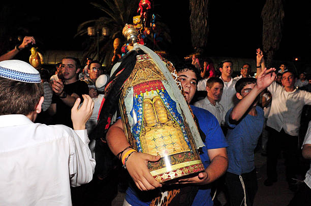 Celebrating Jewish Holiday Simchat Torah in a Synagogue Sderot, Israel - September 7, 2012: Israeli Jewish youth celebrate Simchat Torah by dancing with the scrolls of the Torah at a Synagogue in Sderot, Israel. Simchat Torah is a celebratory Jewish holiday that marks the completion of the annual Torah reading cycle. simchat torah photos stock pictures, royalty-free photos & images