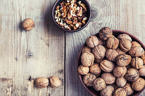 istock walnuts in a clay plate on a wooden background. top view 544585732