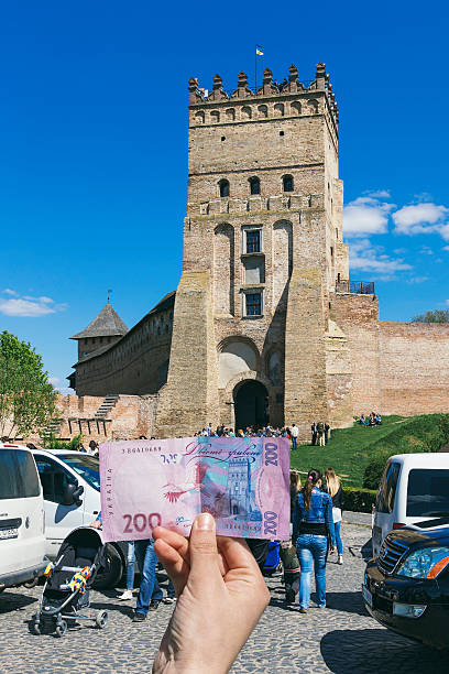 castle in Lutsk castle in Lutsk, Ukraine. in front of the castle of a crowd of tourists. girl holds 200 hryvnia against the backdrop of the castle. bailey castle stock pictures, royalty-free photos & images