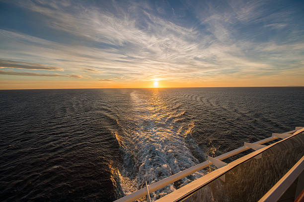 Wake in sea seen from boat during sunset. Cropped image of cruise ship is sailing on water. Sunlight is reflecting on water.