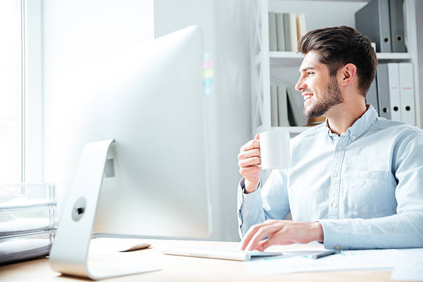 istock Young smiling businessman drinking coffee and looking away in office 544595138