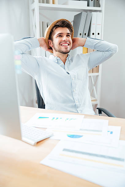 istock Cheerful young man in hat sitting and relaxing in office 544597044