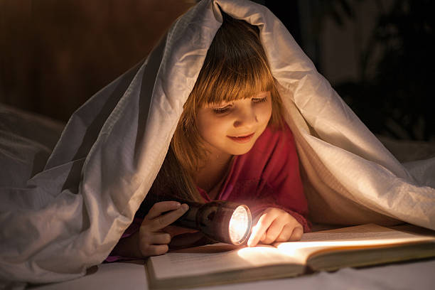 istock young girl reading book under the covers with flashlight 544598090
