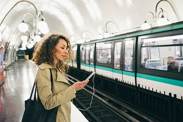 Cheerful woman on the phone, subway train on background Cheerful woman listening to music from her smartphone while waiting for the train to go home, subway train on background. public transportation photos stock pictures, royalty-free photos & images