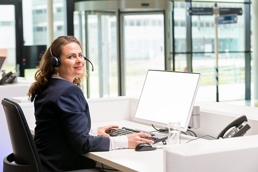 Receptionist looking at camera at the frontdesk of an office, or hotel