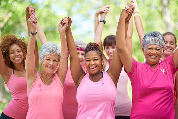 We’re survivors! Portrait of a group of enthusiastic woman taking part in a fitness event to raise awareness for breast cancer non profit organization photos stock pictures, royalty-free photos & images