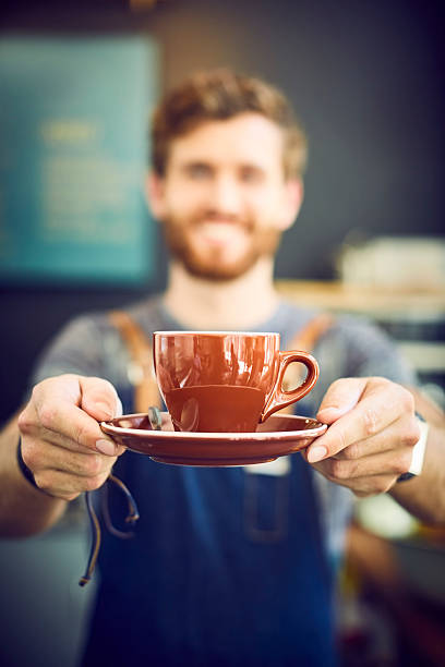 Male barista offering coffee in cafe