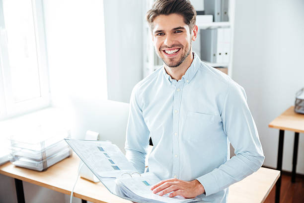 istock Cheerful young businessman holding folder with documents in office 544602842