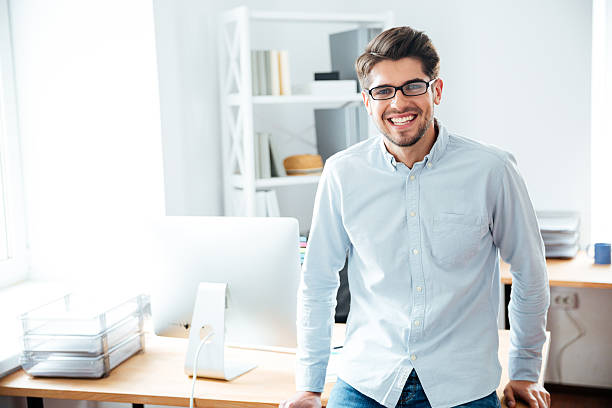 istock Smiling young businessman in glasses standing in office 544604010