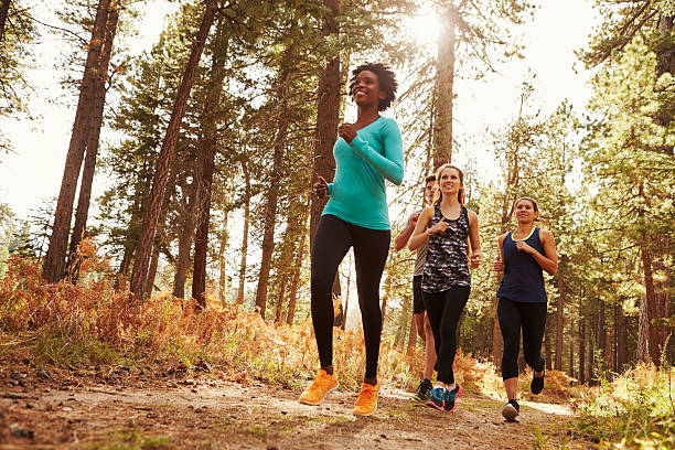 anteriore vista di quattro adulti corsa nella foresta, basso - running jogging african descent nature foto e immagini stock