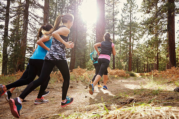 groupe de jeune adulte femme courir dans la forêt, le dos - cross country running running jogging black and white photos et images de collection