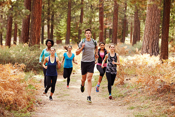 groupe de jeunes amis adultes courir dans la forêt - cross country running running jogging black and white photos et images de collection