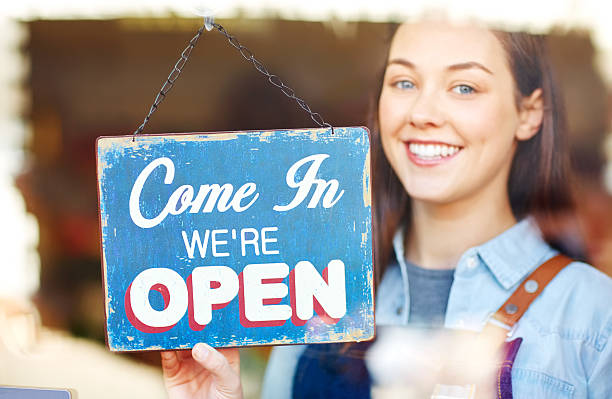 istock Smiling florist showing open sign at shop window 544651842