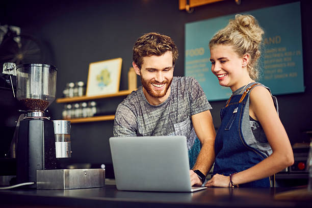 istock Smiling baristas using laptop at counter 544654812