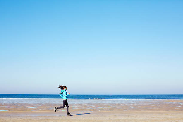 istock Dedicated fit woman jogging on beach against blue sky 544658946