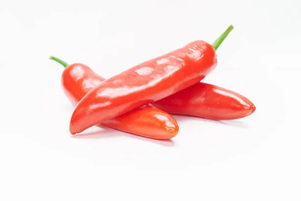 Three red chilli peppers on white.