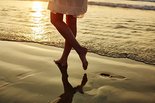 istock Woman walking barefoot on wet shore during sunset 544660036