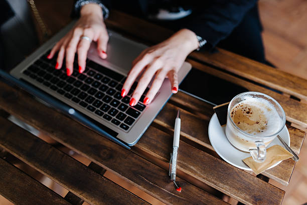 Woman hands typing on a laptop Business woman typing her report in a coffeeshop. red nail polish stock pictures, royalty-free photos & images