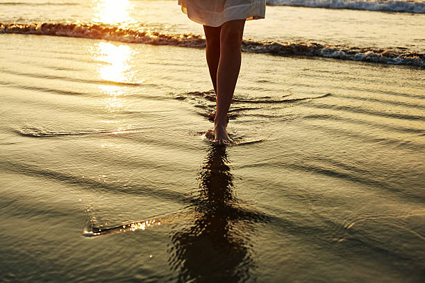 istock Low section of woman walking on wet shore 544661672