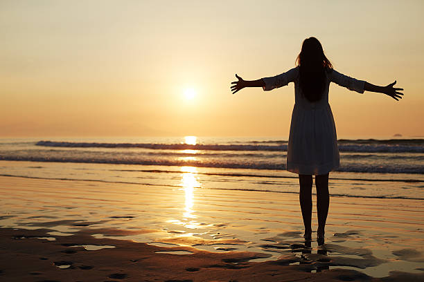 istock Full length woman standing arms outstretched on beach during sun 544662080